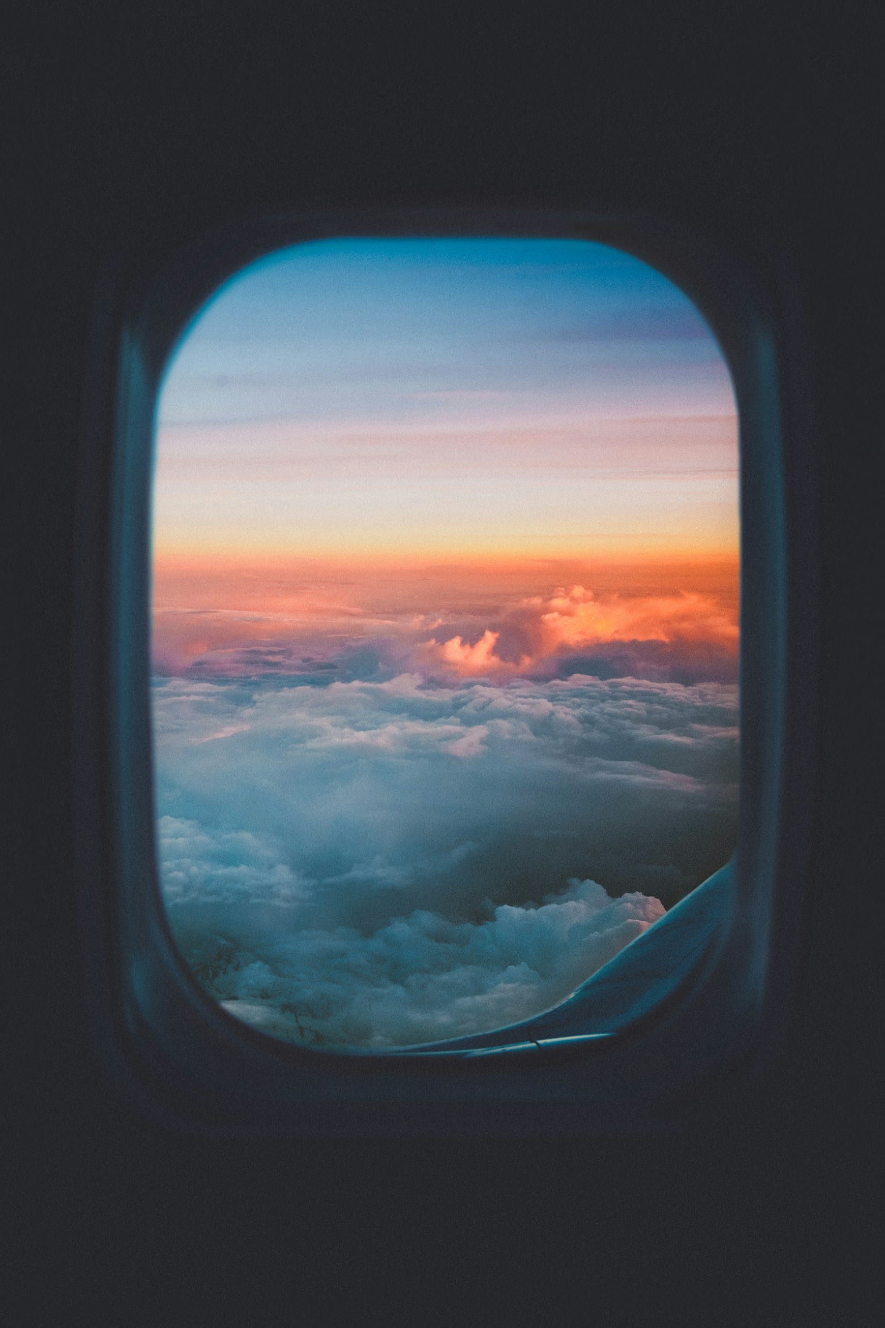 Plane window view of clouds at sunset, golden light over the horizon